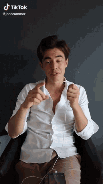 a man in a white shirt is sitting in a chair with a phone in front of him and a tiktok watermark on the top