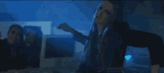 a woman is standing in a dark room with her arms outstretched and making a funny face .
