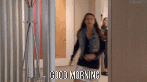 a woman is standing in a hallway and saying good morning .
