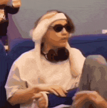 a woman wearing sunglasses and a headband sits in a chair