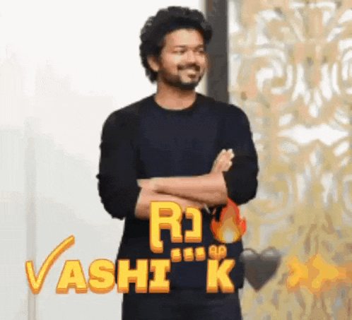 a man in a black shirt is standing with his arms crossed in front of a wall with the word rashi k on it .