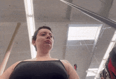 a woman in a black tank top is standing in a room