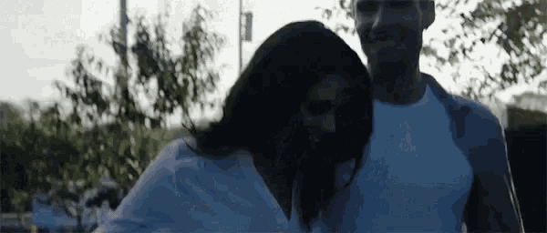 a man and a woman are standing next to each other and hugging each other .