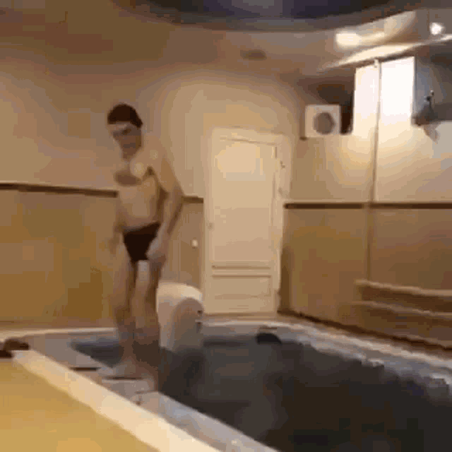 a man is jumping into a swimming pool in a room .
