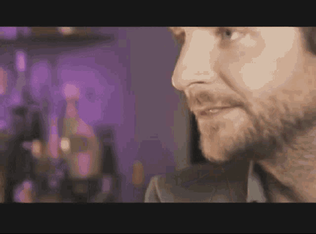 a man with a beard is standing in front of a purple background