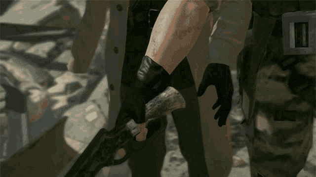 a man wearing black gloves is holding a gun with the letter t on it