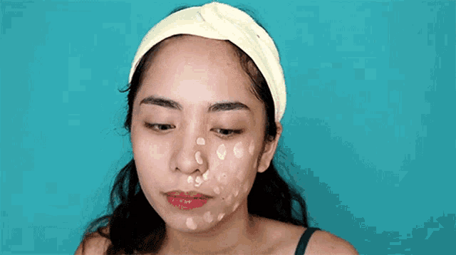 a woman with a headband on her head has a lot of spots on her face .