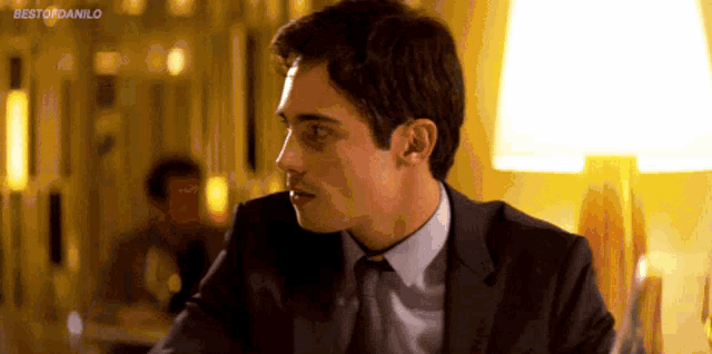 a man in a suit and tie is sitting in front of a lamp with the words bestofdanilo on the bottom