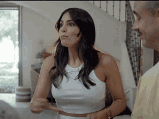 a woman in a white crop top is talking to a man