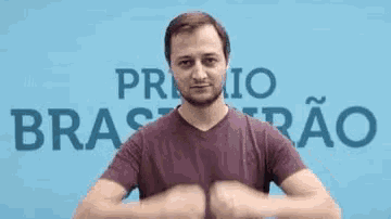 a man is making a heart shape with his hands in front of a blue wall .