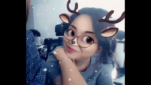 a girl with glasses and antlers on her face looks at the camera