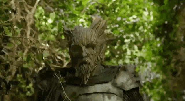 a man in a tree costume is standing in the woods .