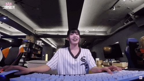 a girl wearing a striped shirt with the letter s on it is typing on a keyboard