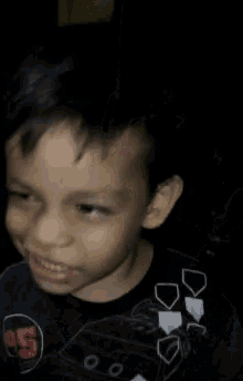 a young boy wearing a black shirt with the number 95 on it makes a funny face .