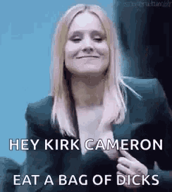 a woman in a suit is smiling and saying `` hey kirk cameron eat a bag of dicks `` .