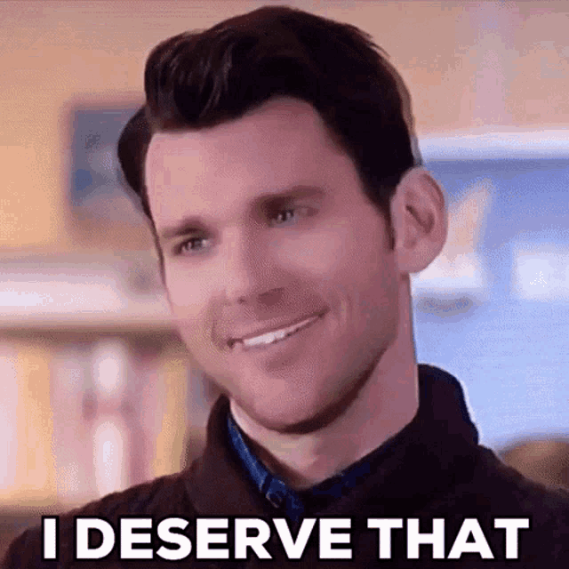 a man is smiling and saying `` i deserve that '' while looking at the camera .
