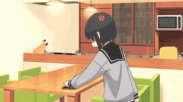 a girl sitting at a table with an angry face on her head
