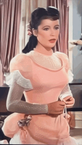 a woman in a pink dress is sitting in front of a piano