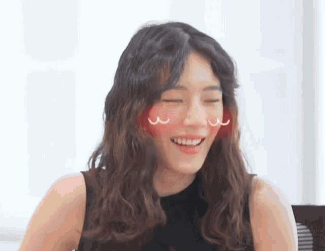 a woman is smiling with her eyes closed and a red heart on her cheek