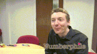 a man sitting at a table with the name numberphile written on the bottom