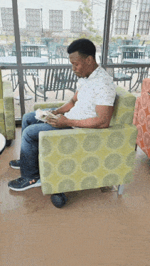 a man sits in a chair reading a book in front of a window
