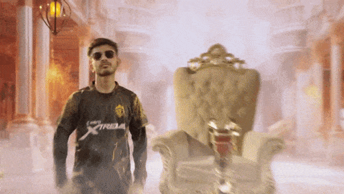 a man wearing sunglasses and a shirt that says xtribe stands in front of a chair