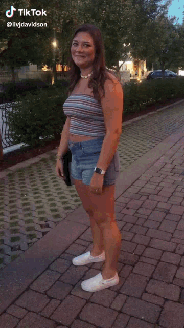 a woman is laying on a brick sidewalk with a tiktok video behind her