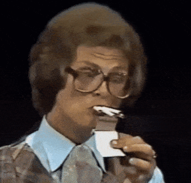 a man wearing glasses is eating a piece of paper .