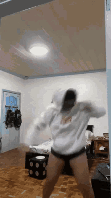 a person in a white sweatshirt with the word supreme on it is dancing in a living room
