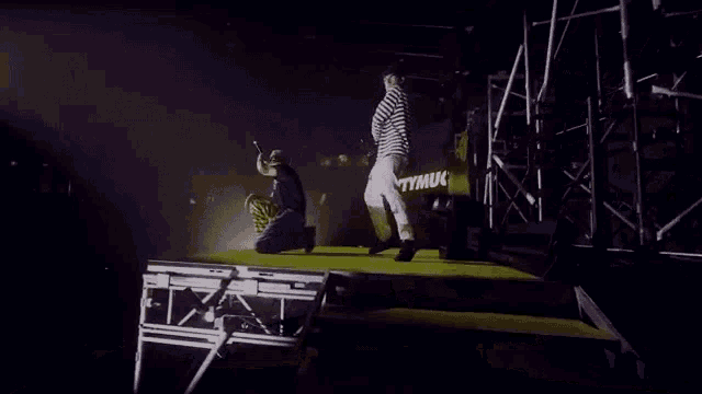 a man singing into a microphone while another man kneeling down