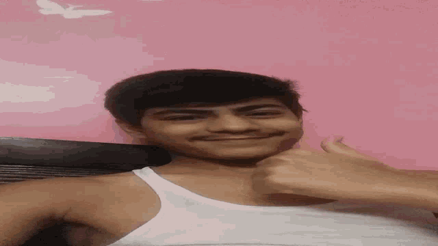a man in a white tank top is giving a thumbs up .