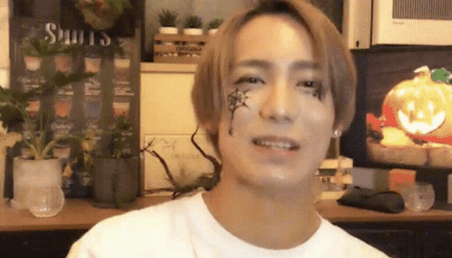 a man with a spider on his face is smiling in front of a sign that says ' shots '