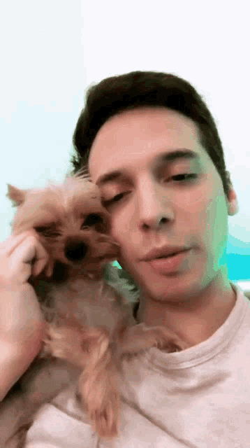 a man is holding a small dog in his lap