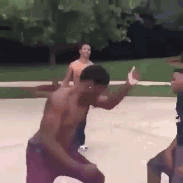 a shirtless man is dancing on a basketball court while another man watches .
