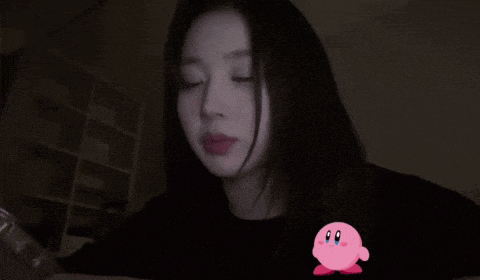 a woman with her tongue out is wearing a black shirt with a kirby sticker on it .
