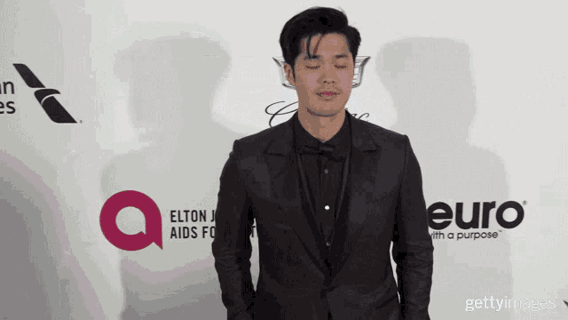 a man in a suit stands in front of a red carpet that says euro