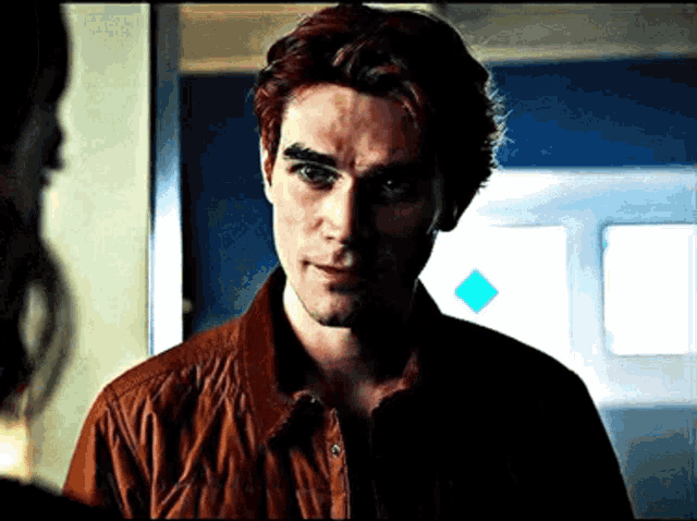 a man with red hair and a brown jacket is looking at a woman .