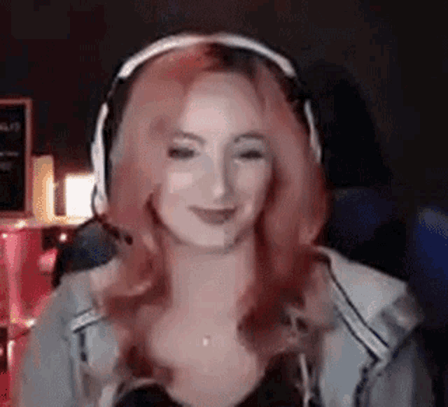 a woman is wearing headphones and smiling while sitting in front of a computer screen .