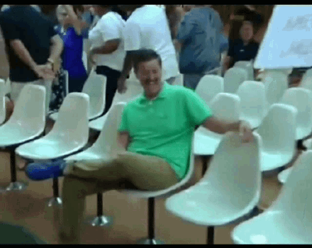 a man in a green shirt is sitting on a white chair