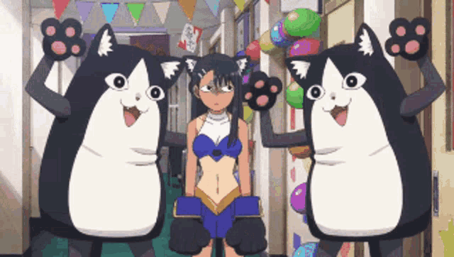 a girl in a blue top is standing next to two black and white cats