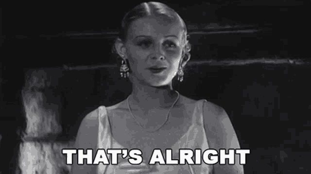 a woman is standing in a dark room and saying `` that 's alright '' in a black and white photo .