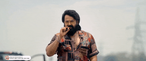 a man with a beard and glasses is smoking a cigarette in front of a no smoking sign
