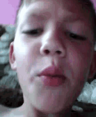 a close up of a young boy 's face with his eyes closed and his mouth open .