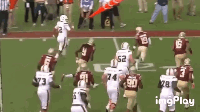 a group of football players are running on a field and one player has the number 52 on his jersey