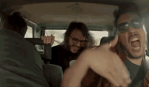 a group of men are riding in the back of a car .