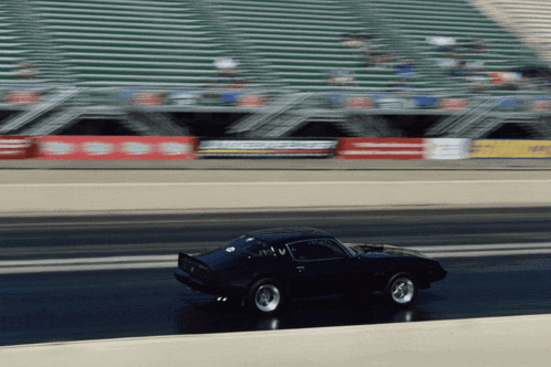 a black car is driving down a race track with a sign behind it that says ' simpson ' on it