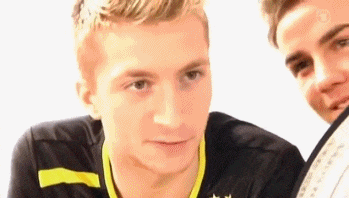 two young men are standing next to each other and one of them is wearing a black and yellow shirt with a star on it .