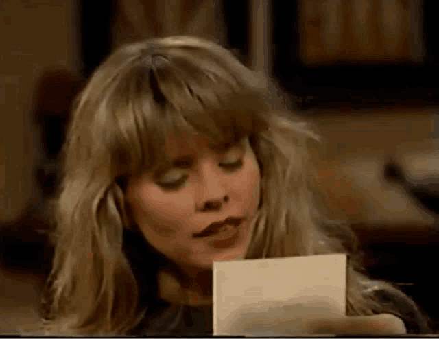 a woman with blonde hair is holding a piece of paper