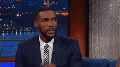 a man in a suit and tie has his finger to his mouth