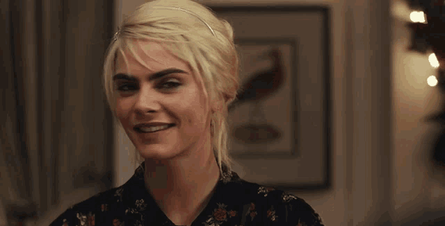 a woman with blonde hair is smiling in front of a picture